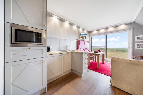 a kitchen with white cabinets and a tv and a table at Fernsicht in Morsum