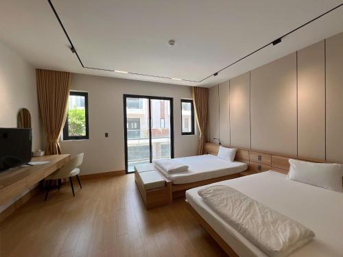 a bedroom with two beds and a desk and a tv at C&M Hotel in Phan Rang–Tháp Chàm
