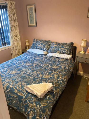a bedroom with a bed with a blue blanket at Gramhor House in Dumfries
