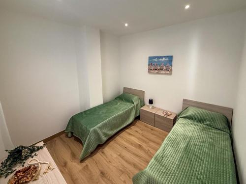 two beds in a room with green sheets at Casa Lo Bianco in Terrasini