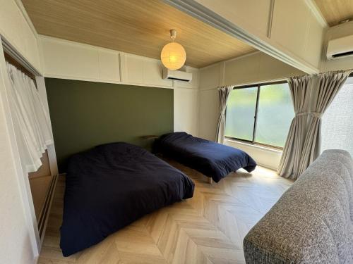 two beds in a room with a window at Sunny side story hotel 九十九里 in Kujukuri