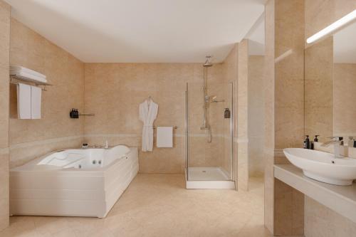 a bathroom with a tub and a sink and a shower at Ramada Plaza by Wyndham Gence in Ganja