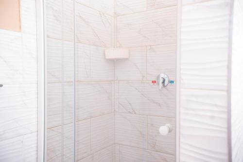 a bathroom with a shower with white tiles at Falcon Lodge (ET) in Bela-Bela
