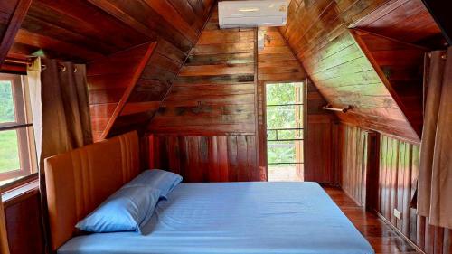 a bed in a room with wooden walls and windows at Meesaeng Homestay in Thalang