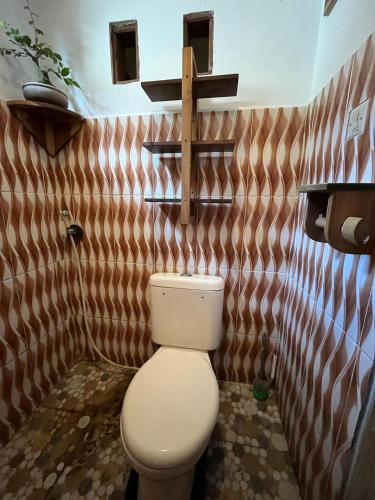 a bathroom with a toilet and a cross on the wall at In Home stay in Bulakbenda