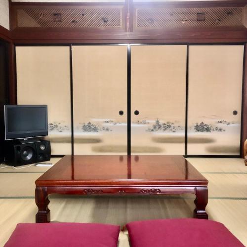 a living room with a table and a tv at 民泊 海男くん家 in Shika