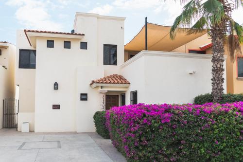 a white house with purple flowers and a palm tree at Outsite Los Cabos in San José del Cabo
