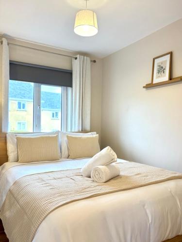 a bedroom with a large white bed with a window at Cobh Coastline Hideaway in Cobh