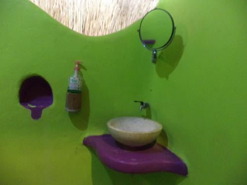 a green bathroom with a sink and a mirror at Topi inn in Padangbai