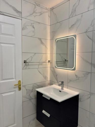 a white bathroom with a sink and a mirror at Cobh Coastline Hideaway in Cobh