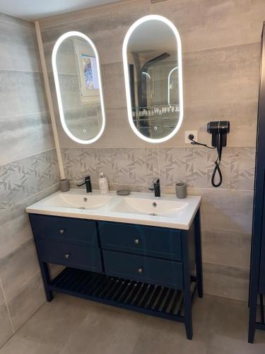 a bathroom with two sinks and two mirrors at Maison Les Cygnes face au lac in Changey