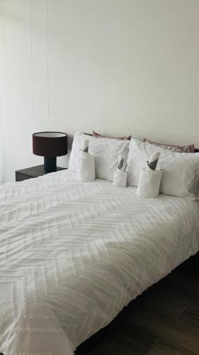 un letto bianco con sopra dei cuscini bianchi di Central Windhoek location a Windhoek