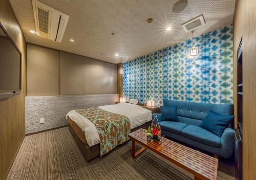 a hotel room with a bed and a blue couch at ホテル彩柏市若柴店 in Kashiwa