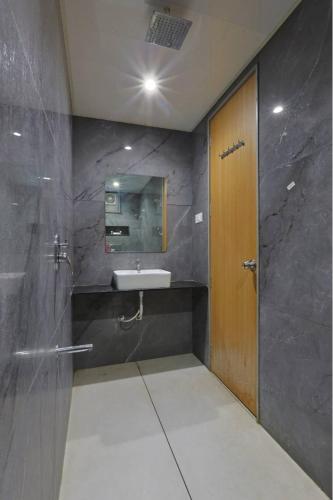 a bathroom with a sink and a wooden door at Hotel Vivanta Inn Somnath in Somnath