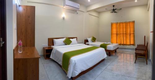 a hotel room with two beds and a window at Siva Bharg Residency in Kovalam