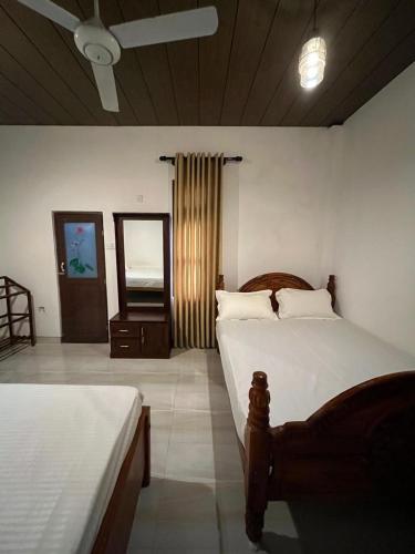 a bedroom with two beds and a mirror in it at Green Sapphire Home Stay in Anuradhapura