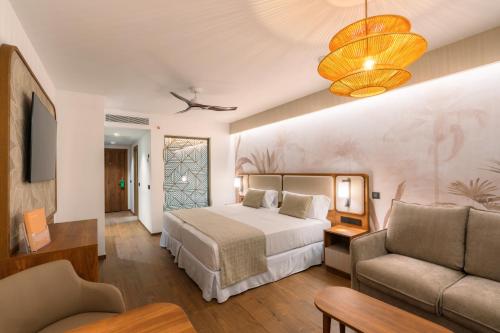 a hotel room with a bed and a couch at Hotel Riu Palace Phuket - All Inclusive in Mai Khao Beach