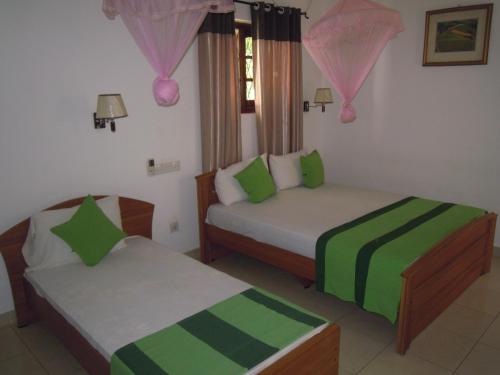 a bedroom with two beds with green and white sheets at Devi Tourist Home in Polonnaruwa