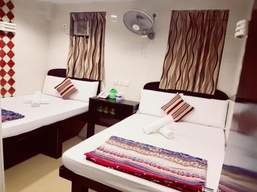 a room with two beds and a fan at Payless A2 Guest House in Hong Kong