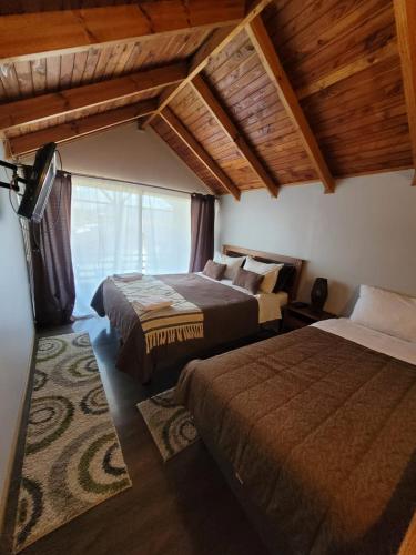 a bedroom with two beds and a large window at Aysen Bike Cabañas in Puerto Aisén