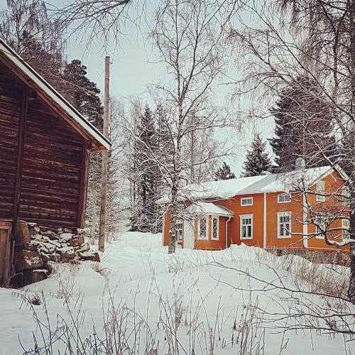 a house is covered in snow next to a cabin at Sundholms Gård - Sundholmin Tila in Kokkola