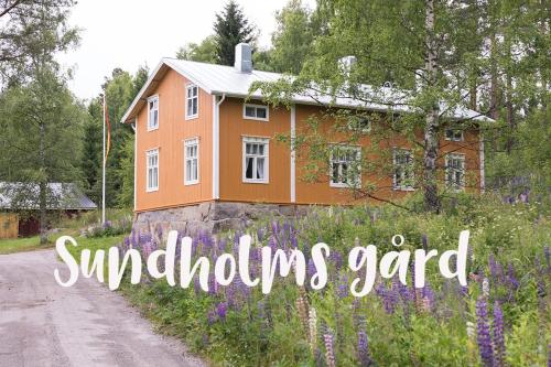 a house with the words symbiosis yard in front of a field of flowers at Sundholms Gård - Sundholmin Tila in Kokkola