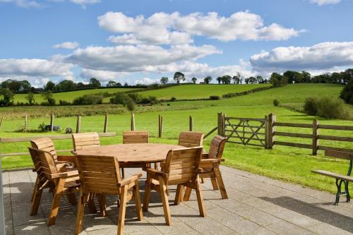 a wooden table and chairs with a field and a fence at Tate's Meadow in Banbridge