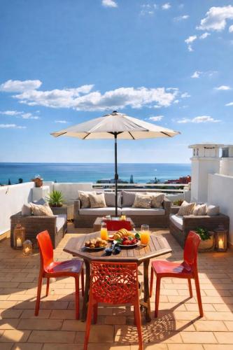 a patio with a table and chairs and an umbrella at Dreamy Sea View Apartment with Access to Private Pool & Stunning Rooftop in Luz