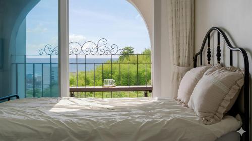 a bedroom with a bed and a large window at Samcheok Sea Road Pension in Samcheok