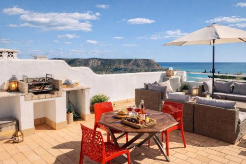 a patio with a table and chairs and an umbrella at Dreamy Sea View Apartment with Access to Private Pool & Stunning Rooftop in Luz