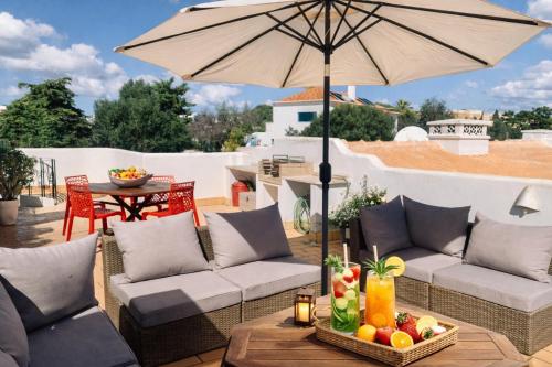 a patio with two couches and an umbrella at Dreamy Sea View Apartment with Access to Private Pool & Stunning Rooftop in Luz