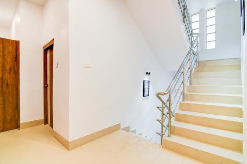 a staircase in a home with white walls and a wooden door at FabHotel Adhiraj Inn in Kolkata