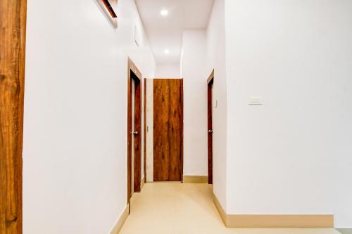 a hallway with white walls and wooden doors at FabHotel Adhiraj Inn in Kolkata