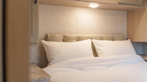 a bed with white sheets and pillows in a room at Sokcho Supuro Caravan in Sokcho