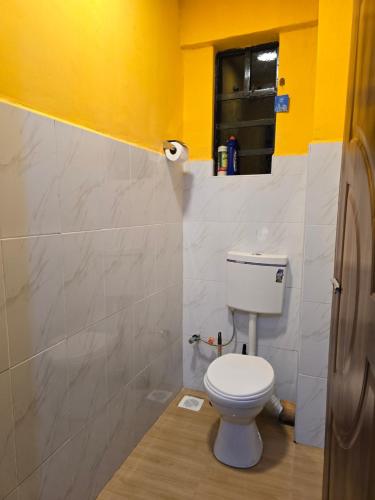a bathroom with a toilet and a yellow wall at Tulivu 2 stays in Nyahururu