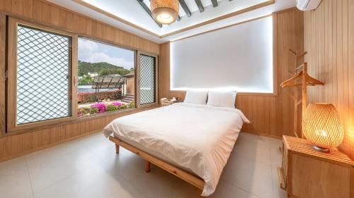 a bedroom with a bed and a large window at Yeosu Elon Pension in Yeosu