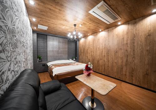 a bedroom with a bed and a couch and a table at ホテルリンクス柏市豊四季店 in Kashiwa