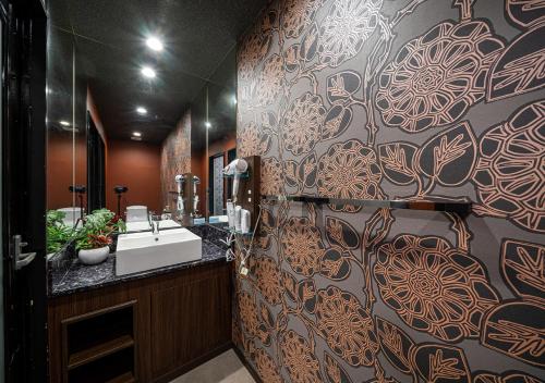 a bathroom with a sink and a patterned wall at ホテルリンクス柏市豊四季店 in Kashiwa
