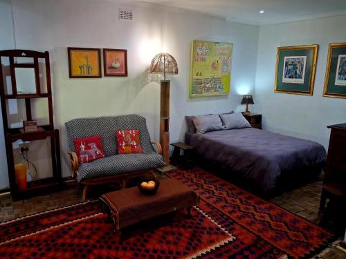 a bedroom with a bed and a couch and a chair at Pennywhistle in Eersterivier