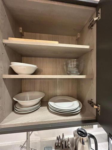 a kitchen cabinet with plates and bowls on shelves at The Courthouse Stylish Serviced Living in Ramsgate