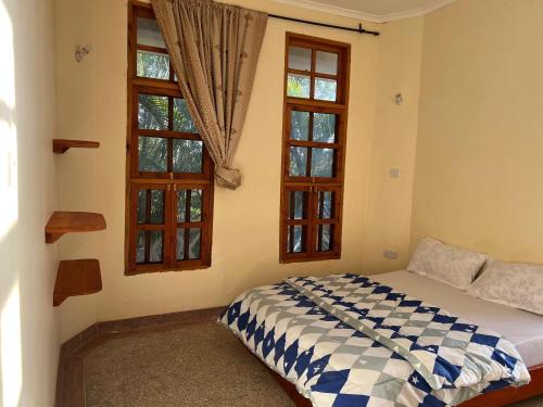 a bedroom with a bed and two windows at The Paradise Inn Kilimanjaro in Moshi