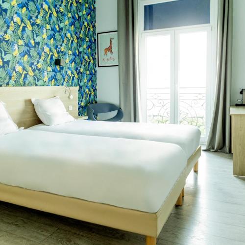 a bedroom with a large white bed and a window at Hotel Aria in Nice