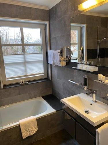 a bathroom with a tub and a sink and a mirror at Schlosshotel Landstuhl in Landstuhl
