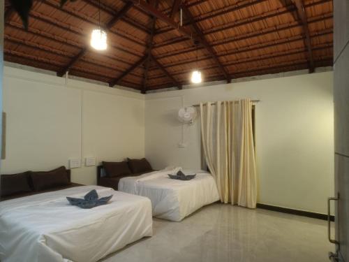a room with two beds with towels on them at Adventure Inn Dandeli in Kurandi