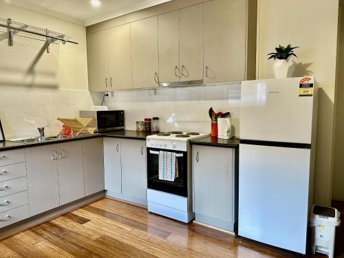 a kitchen with white cabinets and a white refrigerator at Entire Unit in Penguin with Free Parking in Penguin