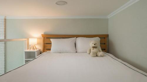 a teddy bear sitting on top of a bed at Yeosu Arungeorida Ocean View Pension in Yeosu