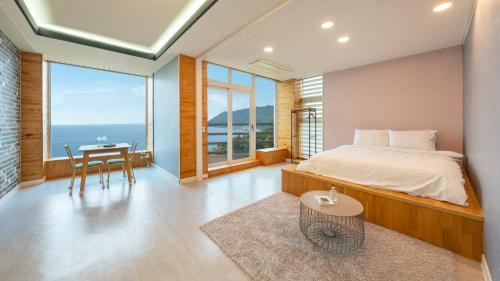 a bedroom with a bed and a table and windows at Geoje Inbito Pension in Op'o