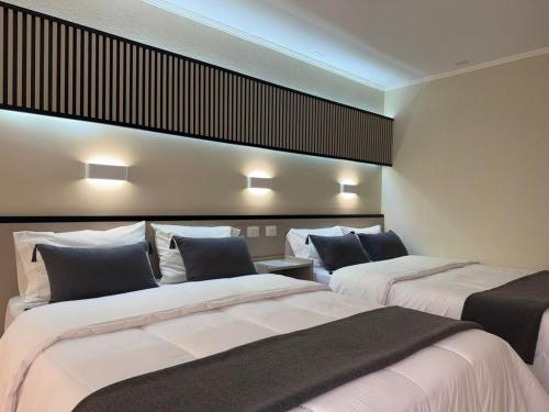 two beds in a room with lights on the wall at Hotel Garden Latorre in Iquique