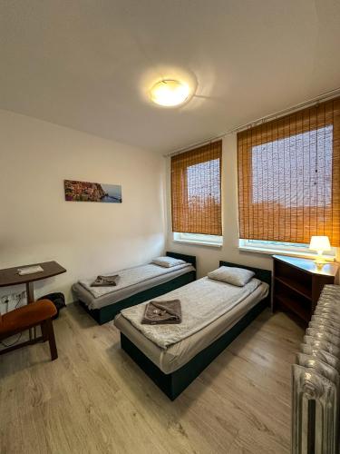 a room with two beds and a desk and windows at Romeo&Julia in Toruń