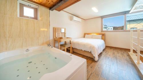 a bathroom with a tub and a bed and a bedroom at Gapyeong Arom Spa Pension in Gapyeong